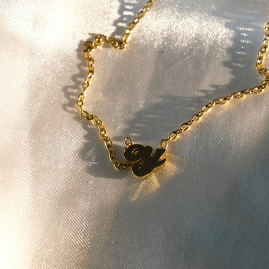Gold dainty oy necklace on white fabric.