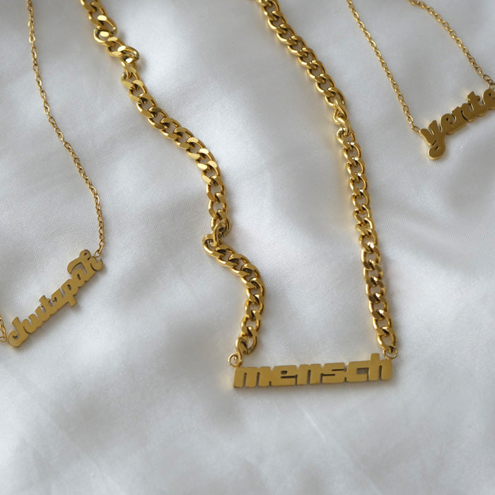 Three gold necklaces on white cloth.
