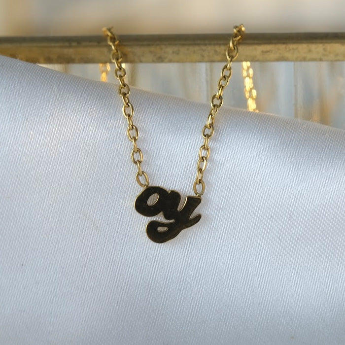 Product shot of gold oy necklace on white cloth.